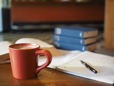 Tasse devant des livres et un cahier : Passer ses examens sereinement grâce à la sophrologie